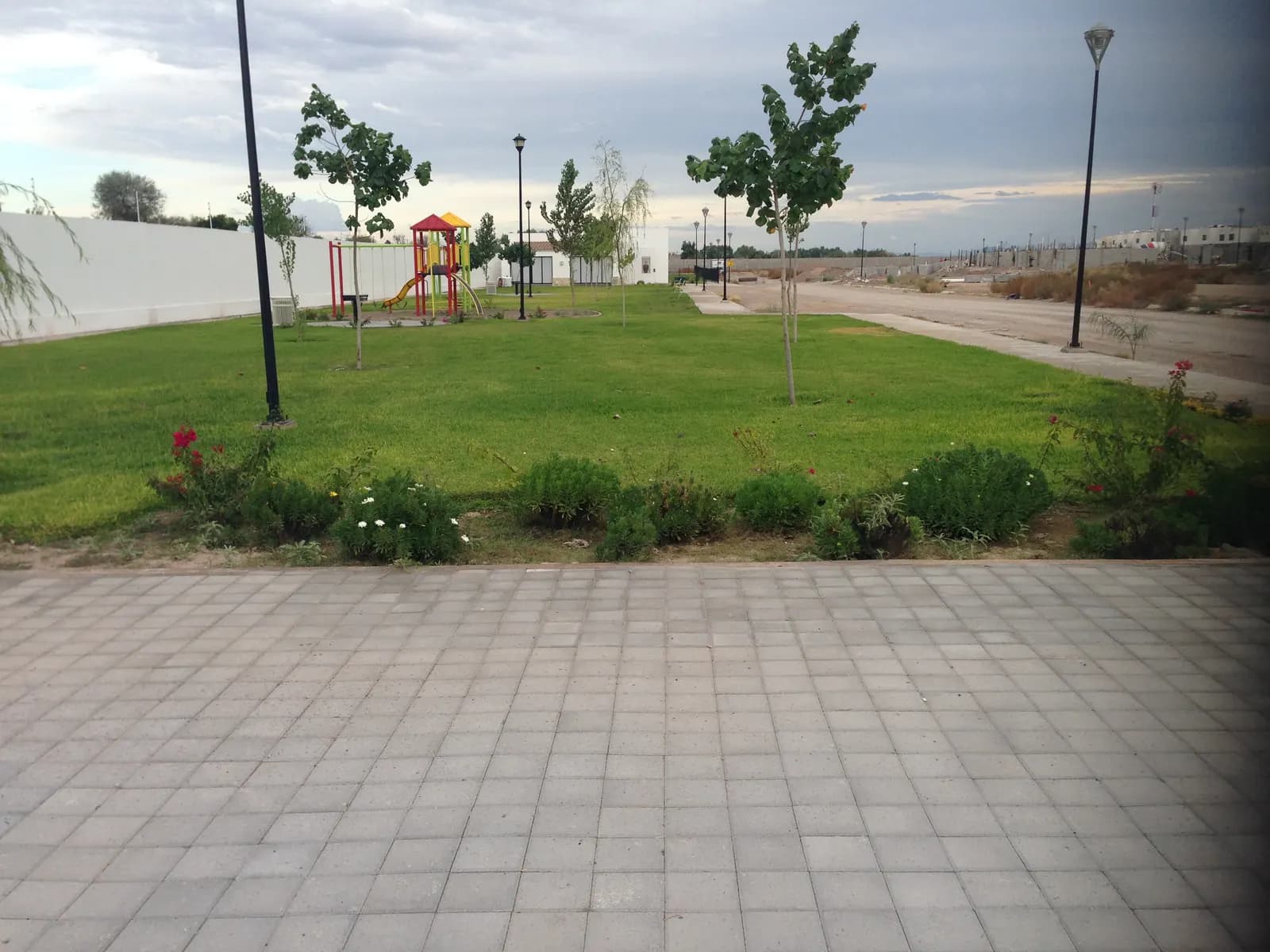 Parque de privada con pasto, árboles jóvenes y juegos