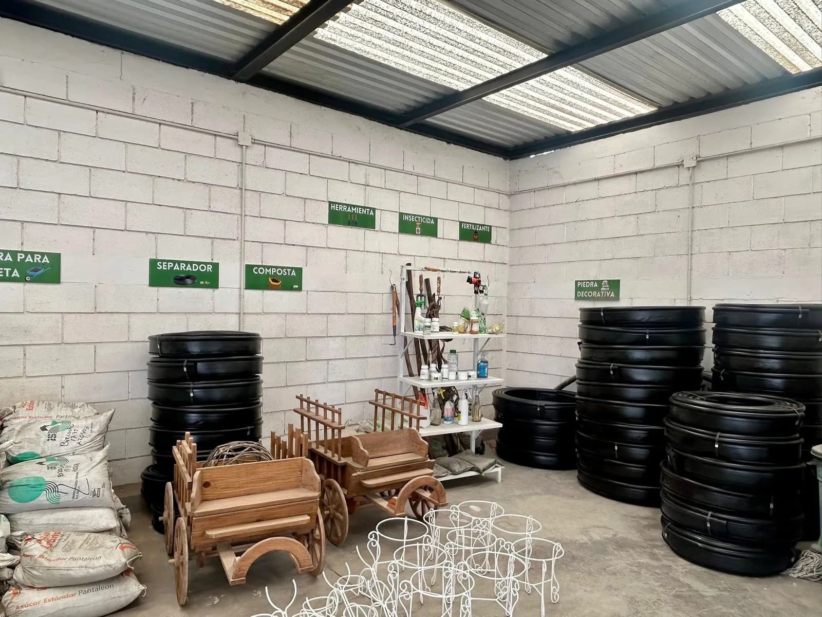 Rollos de manguera de riego y material de jardinería en la bodega de Garden Plus